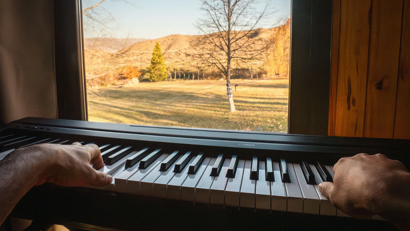 Piano frente a la ventana, vista a la montaña